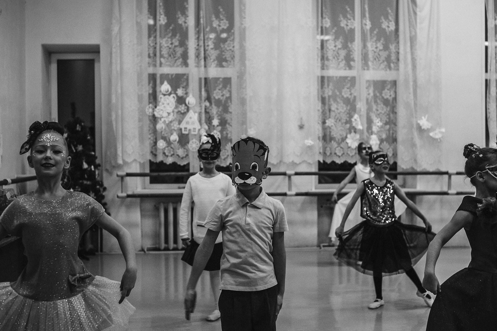Dzieci w maskach ćwiczą choreografię podczas szkolnej próby teatralnej