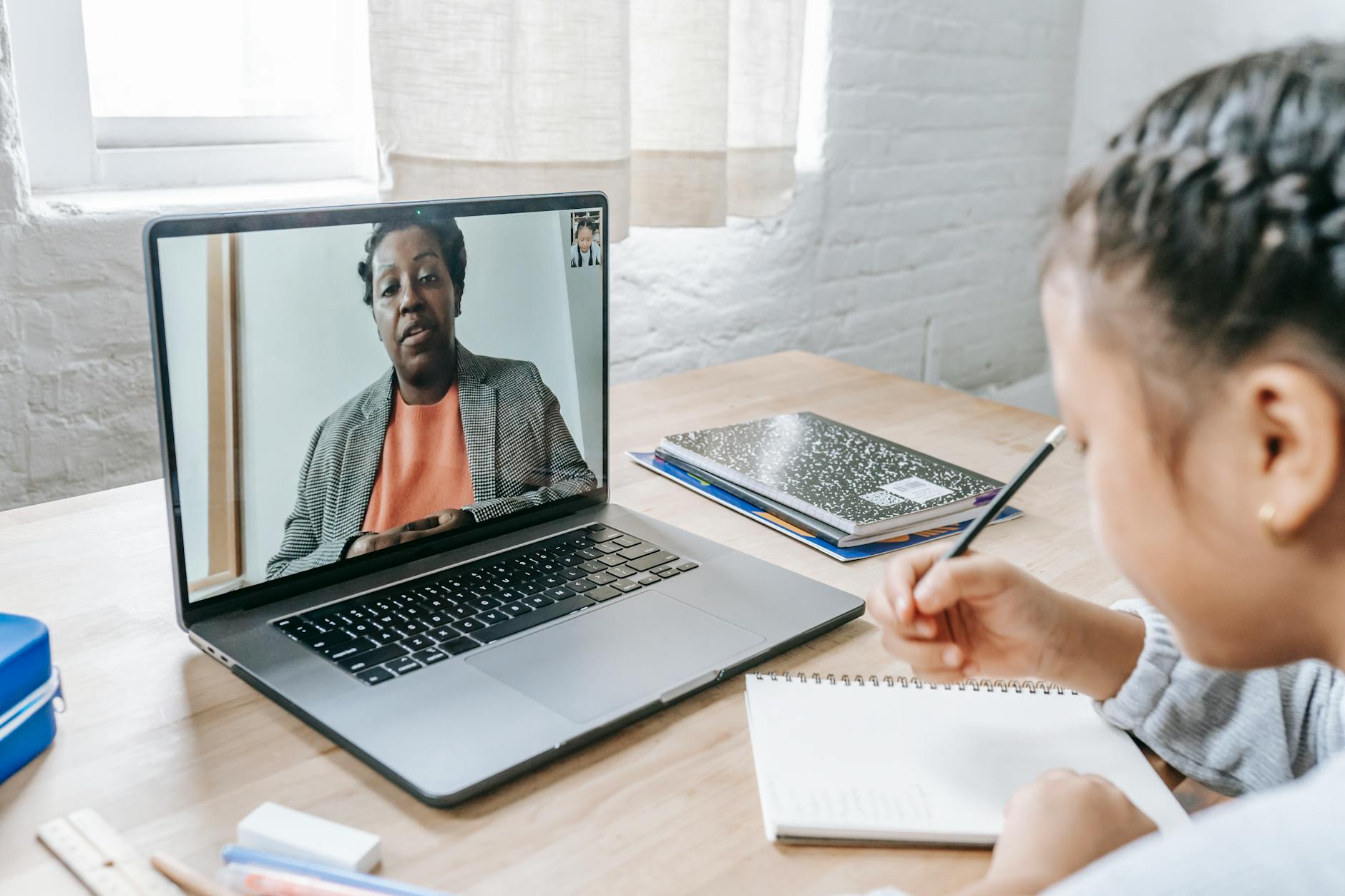 Dziewczynka pisze egzamin online z korepetytorem na laptopie