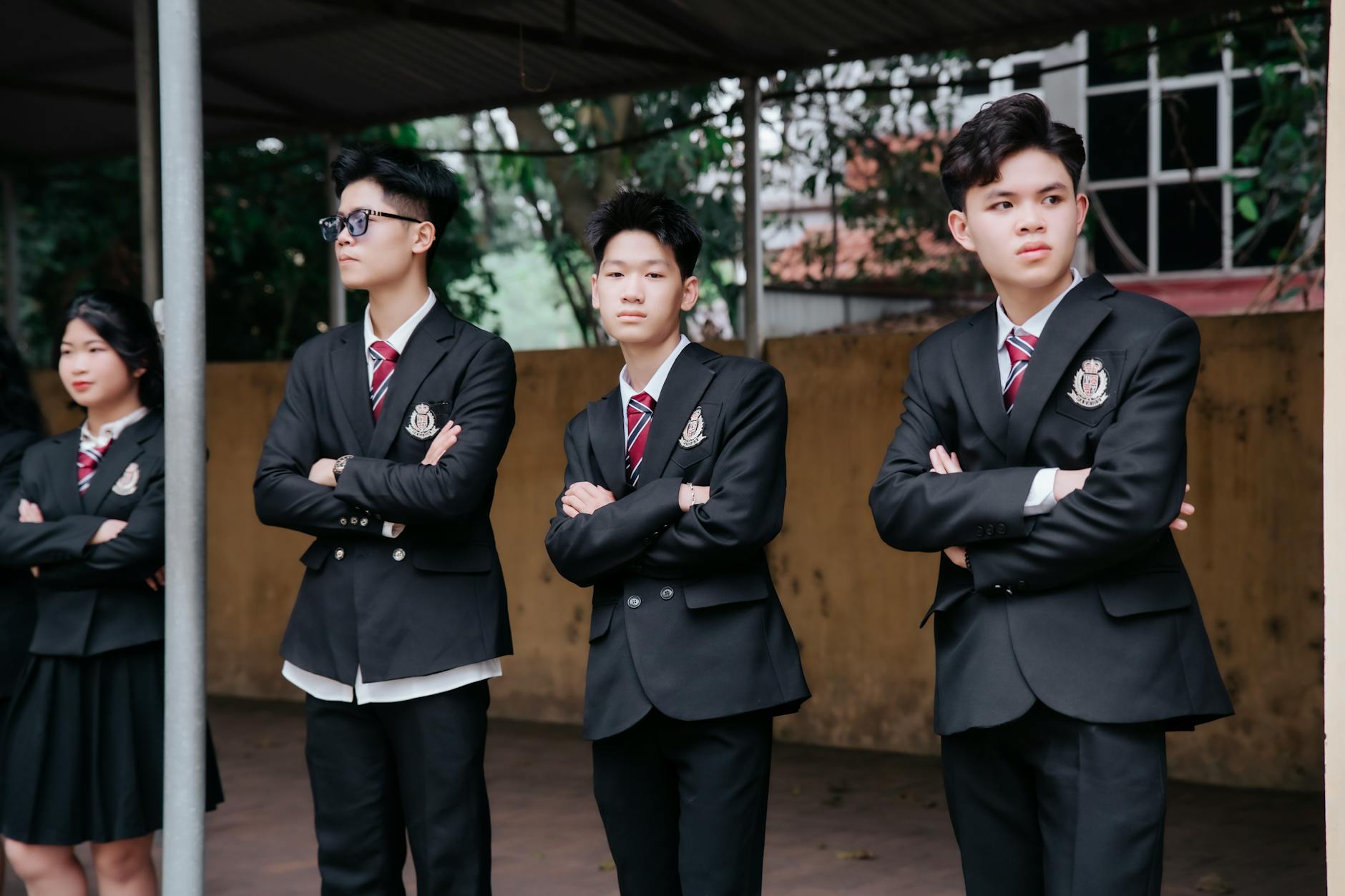 Grupa nastolatków w mundurkach szkolnych stoi pewnie przed szkołą