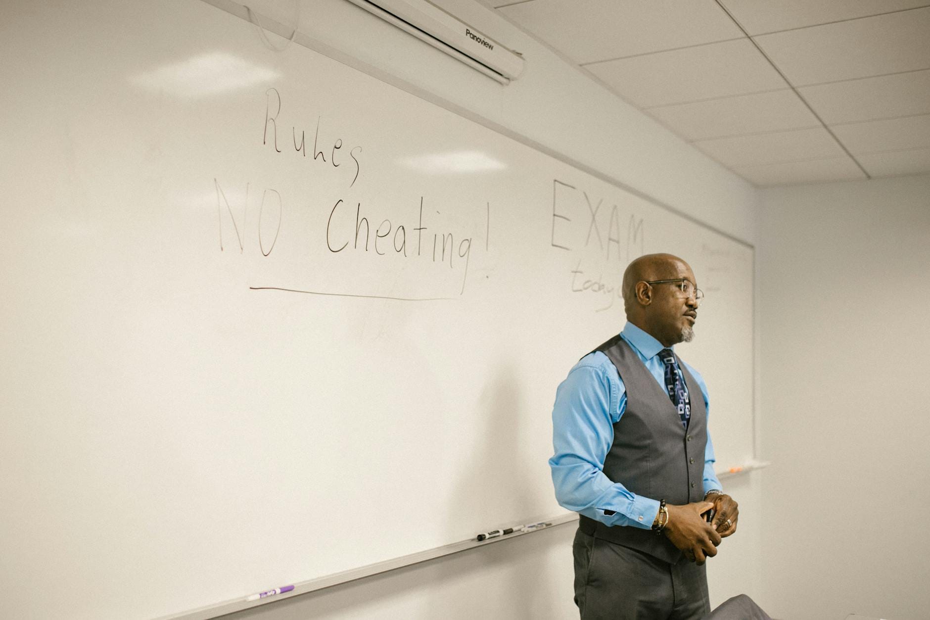 Nauczyciel w klasie tłumaczy uczniom zasady egzaminu na tablicy Nauczyciel w klasie tłumaczy uczniom zasady egzaminu na tablicy