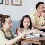 Rodzina pomaga córce w nauce przy stole w salonie