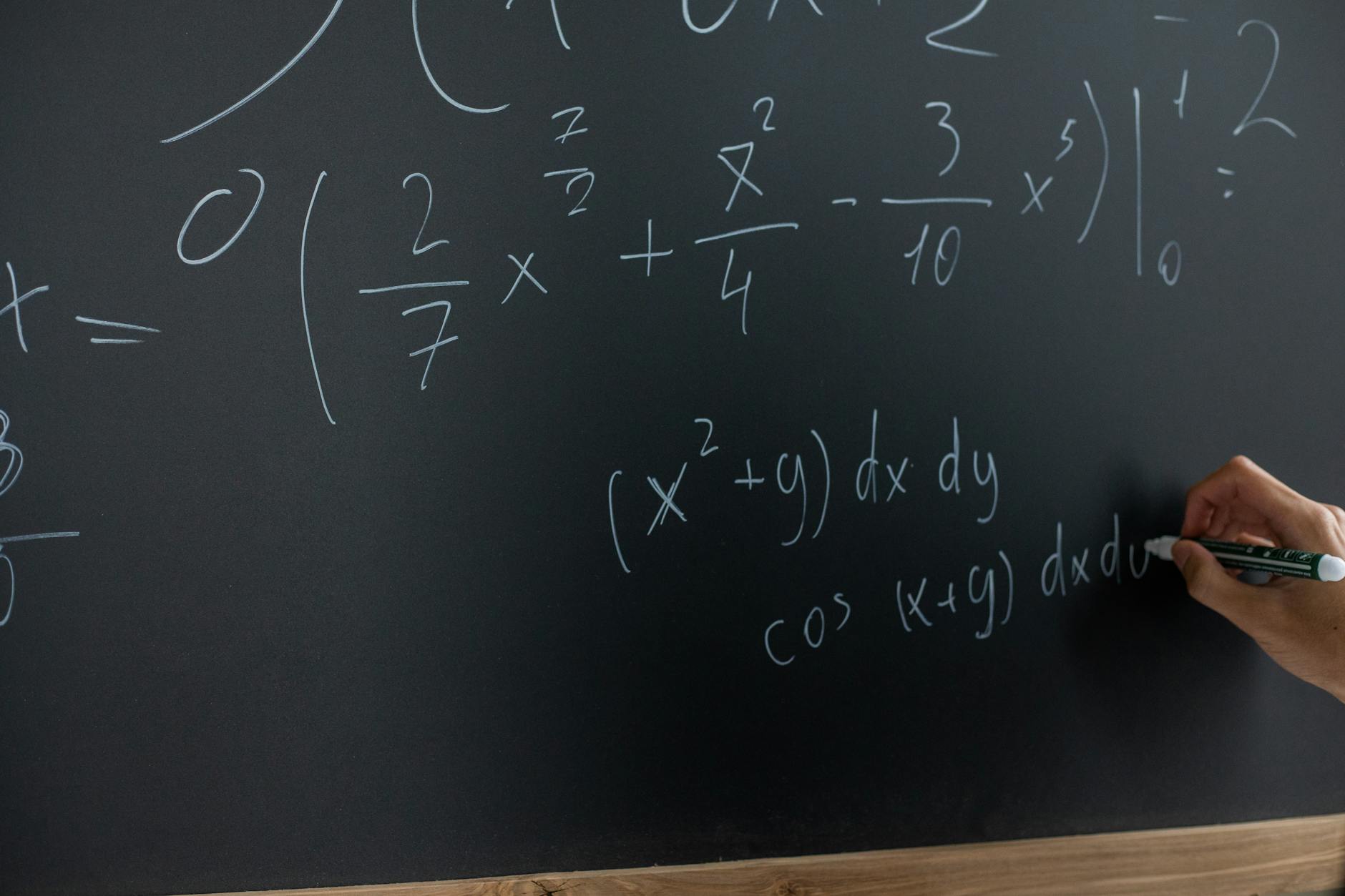 Uczeń zapisuje równania matematyczne kredą na tablicy w klasie