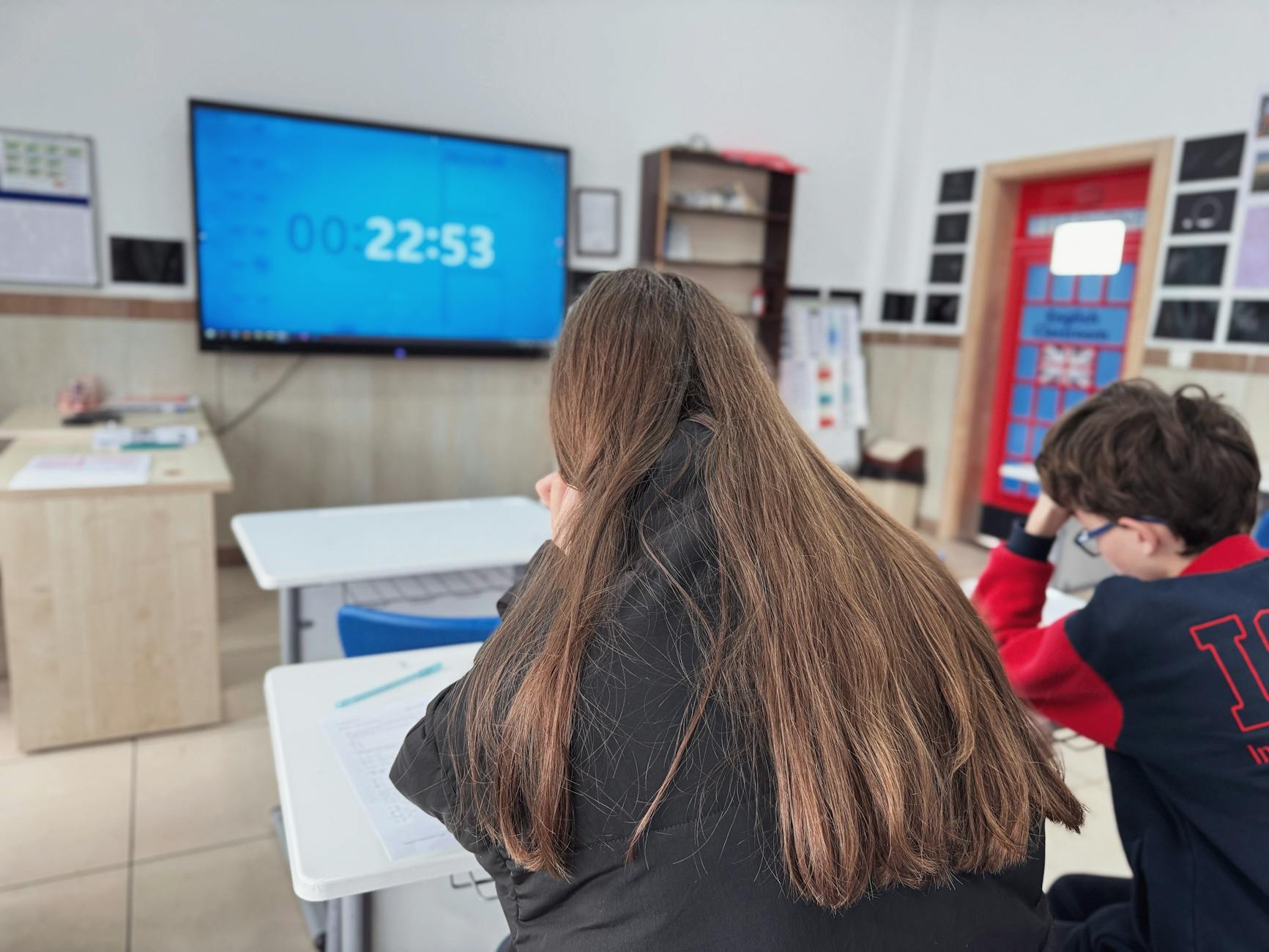 Uczniowie skupieni na teście w nowoczesnej klasie z timerem na ekranie