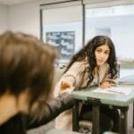 Dwoje studentów przekazuje sobie karteczkę podczas pisania egzaminu