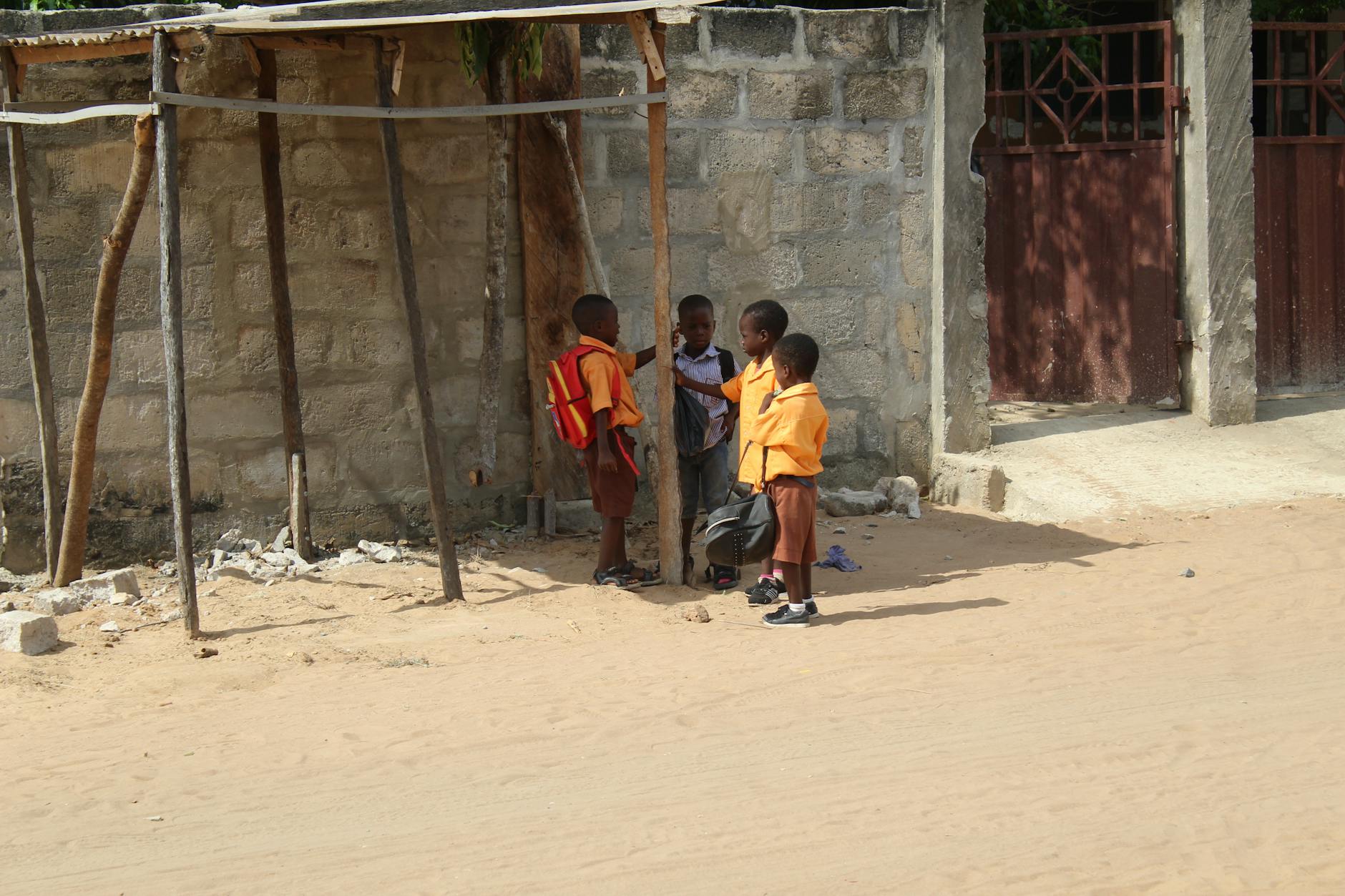 Dzieci w szkolnych mundurkach na słońcu w dzielnicy w Ghanie