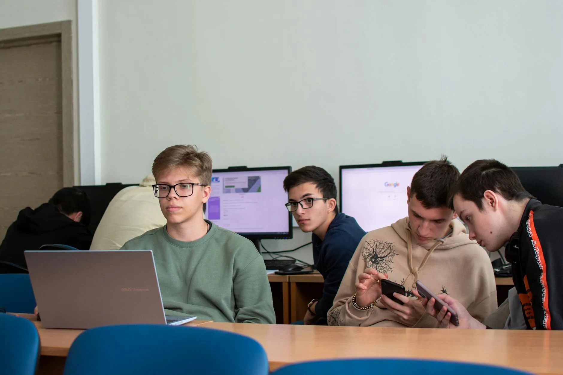 Nastolatki z laptopami i smartfonami w nowoczesnej sali lekcyjnej