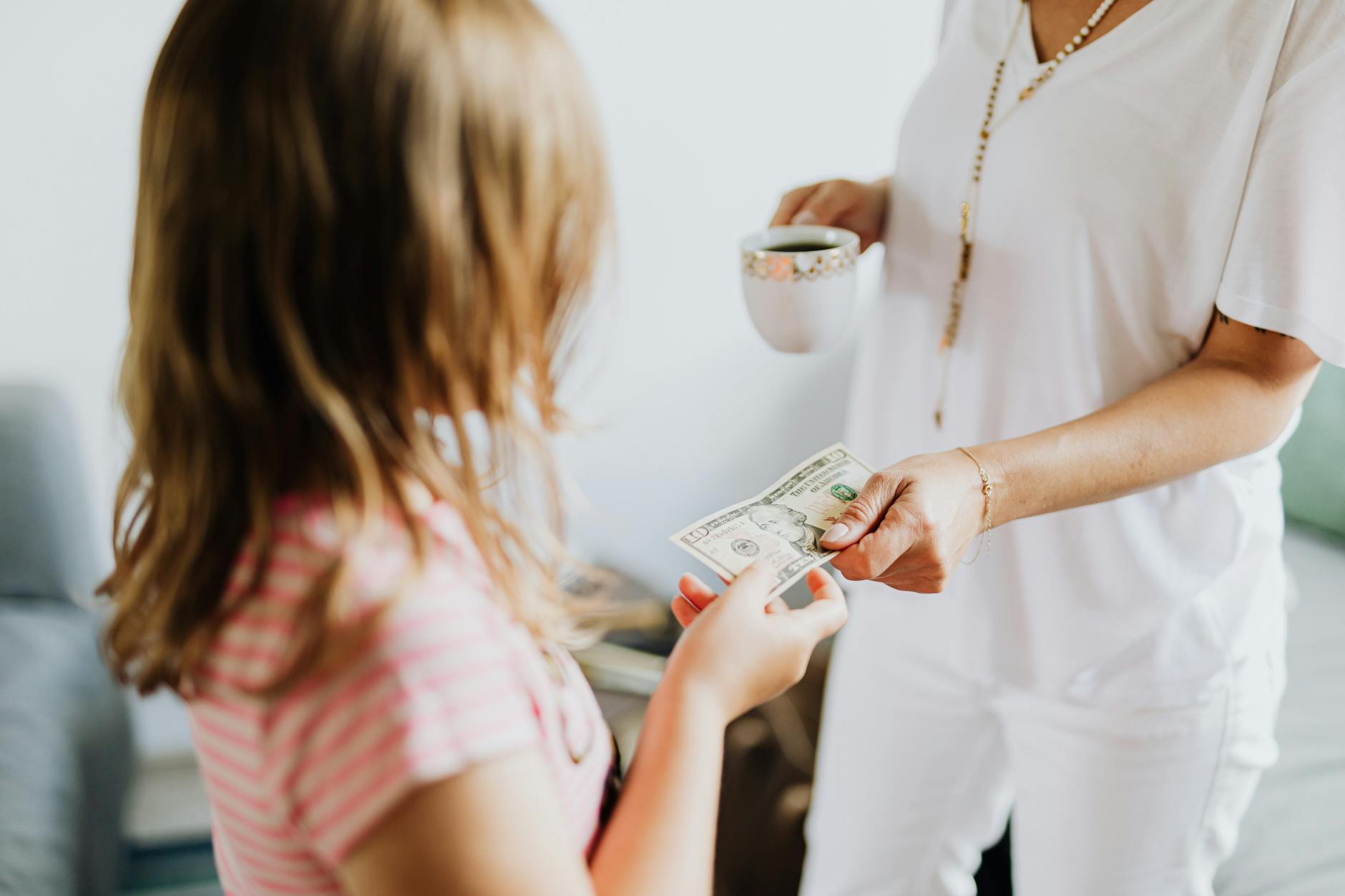 Mama przekazuje córce banknot w domu