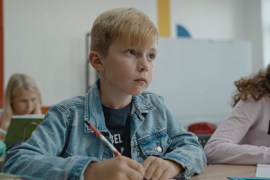 Chłopiec w dżinsowej kurtce uczy się w klasie szkolnej